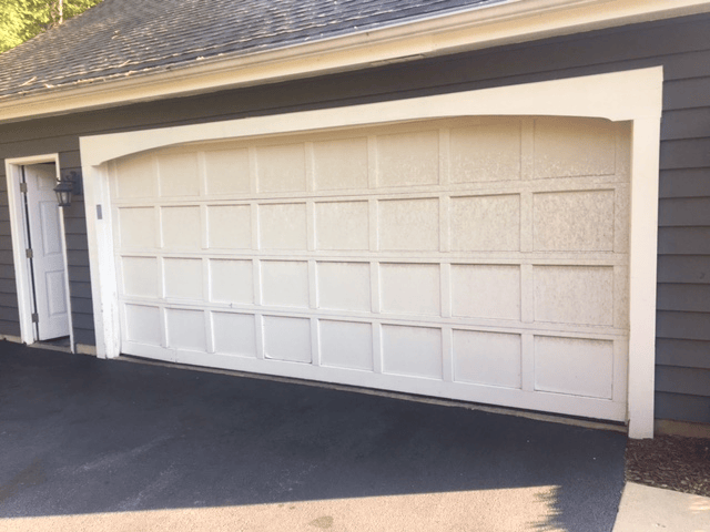 White double garage door on a brick house with a driveway in front