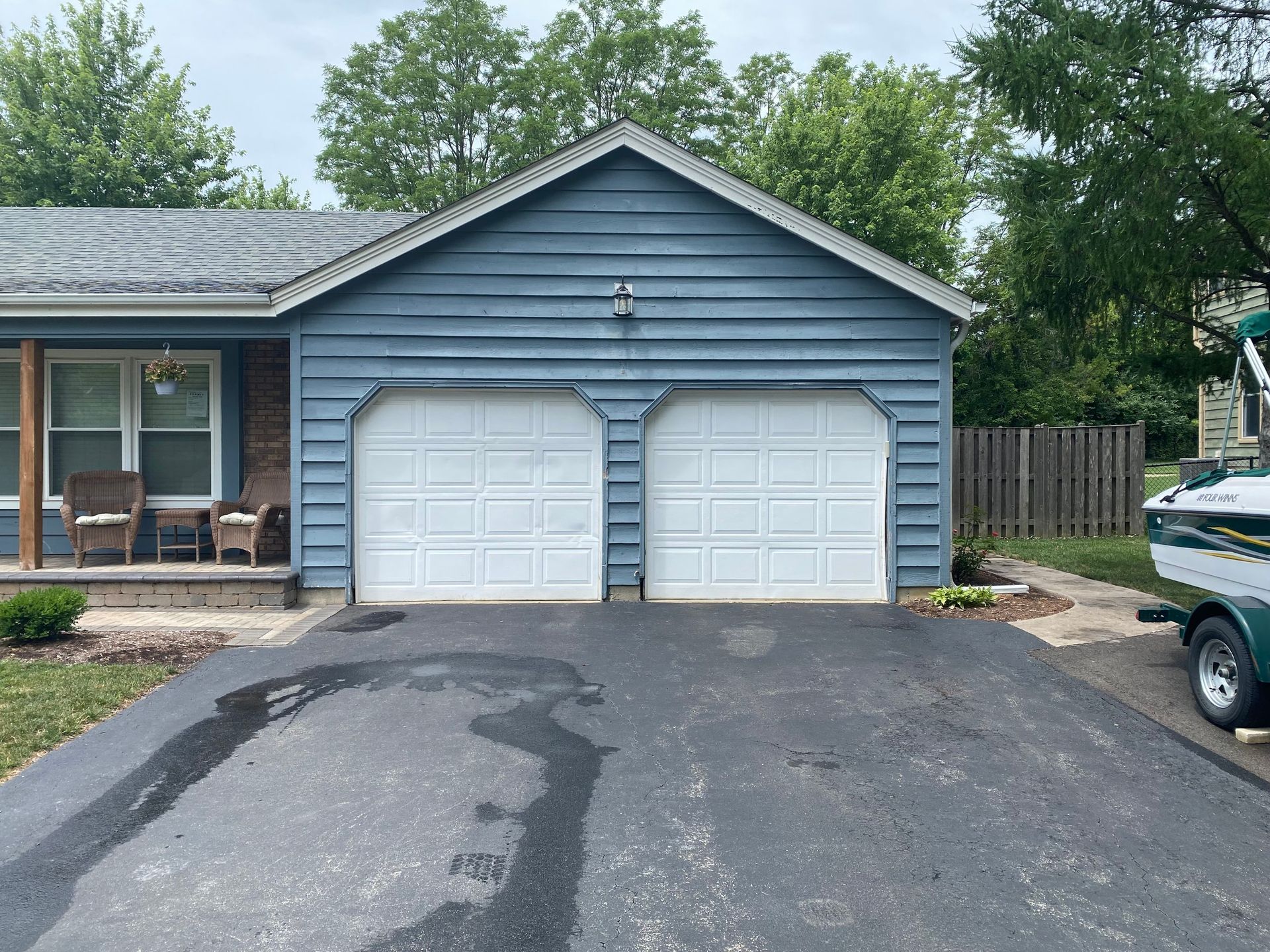 Blue two-car garage with white doors and a driveway in front of a house.