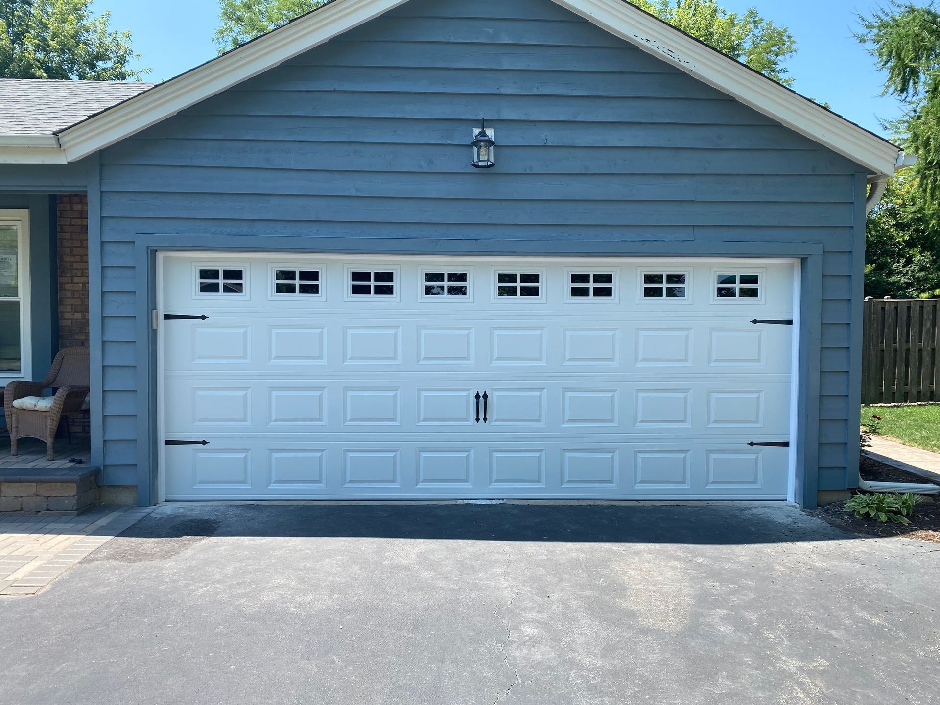 Blue house garage with a white double garage door and small windows above it