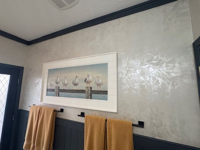 Polished Venetian plaster bathroom wall with framed coastal artwork