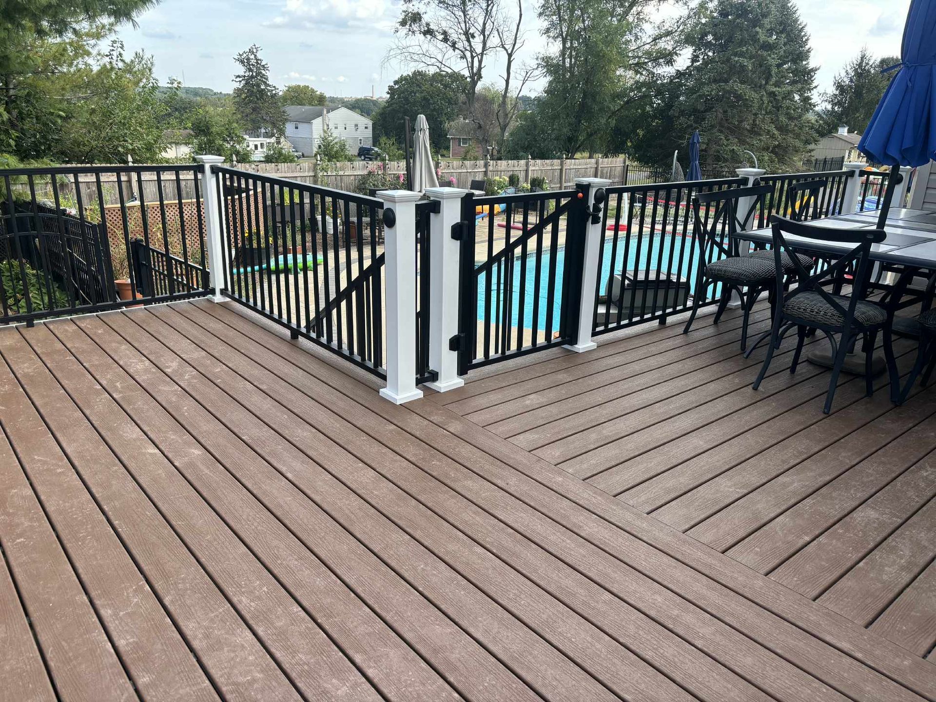 Wooden deck with black and white fence surrounding a pool.