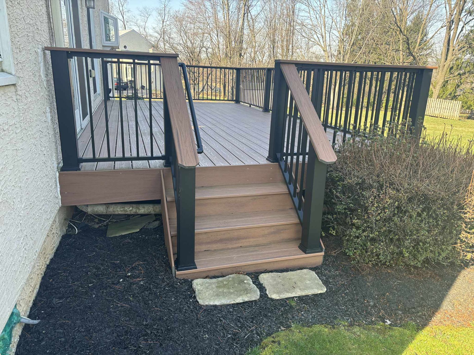 Brown deck with black railing and steps leading to yard.