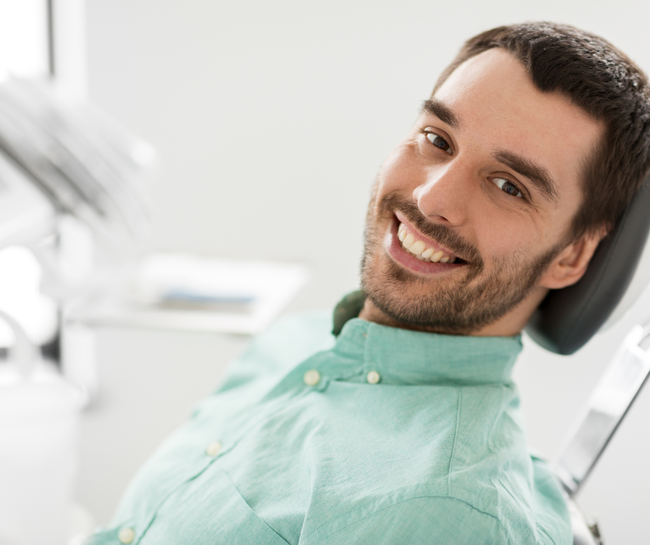 a man is smiling while sitting in a dental chair .