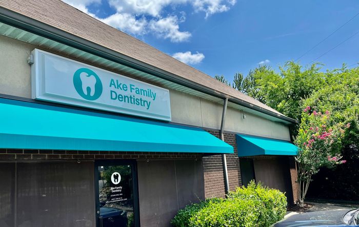 the front of a dental office with a blue awning .