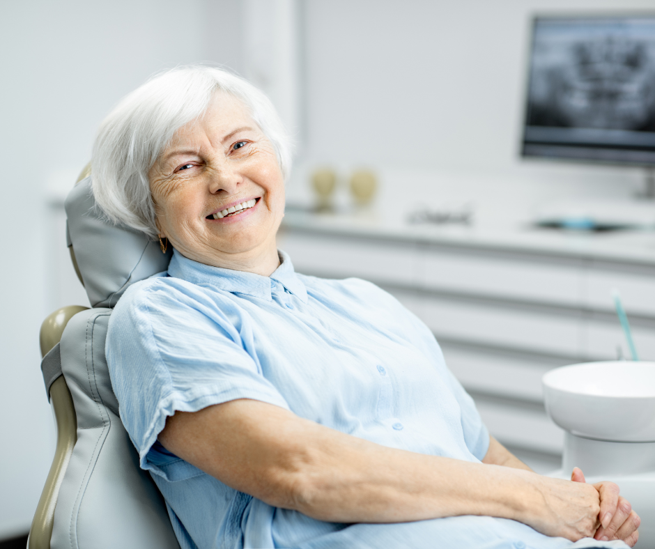 an elderly woman is sitting in a dental chair and smiling .