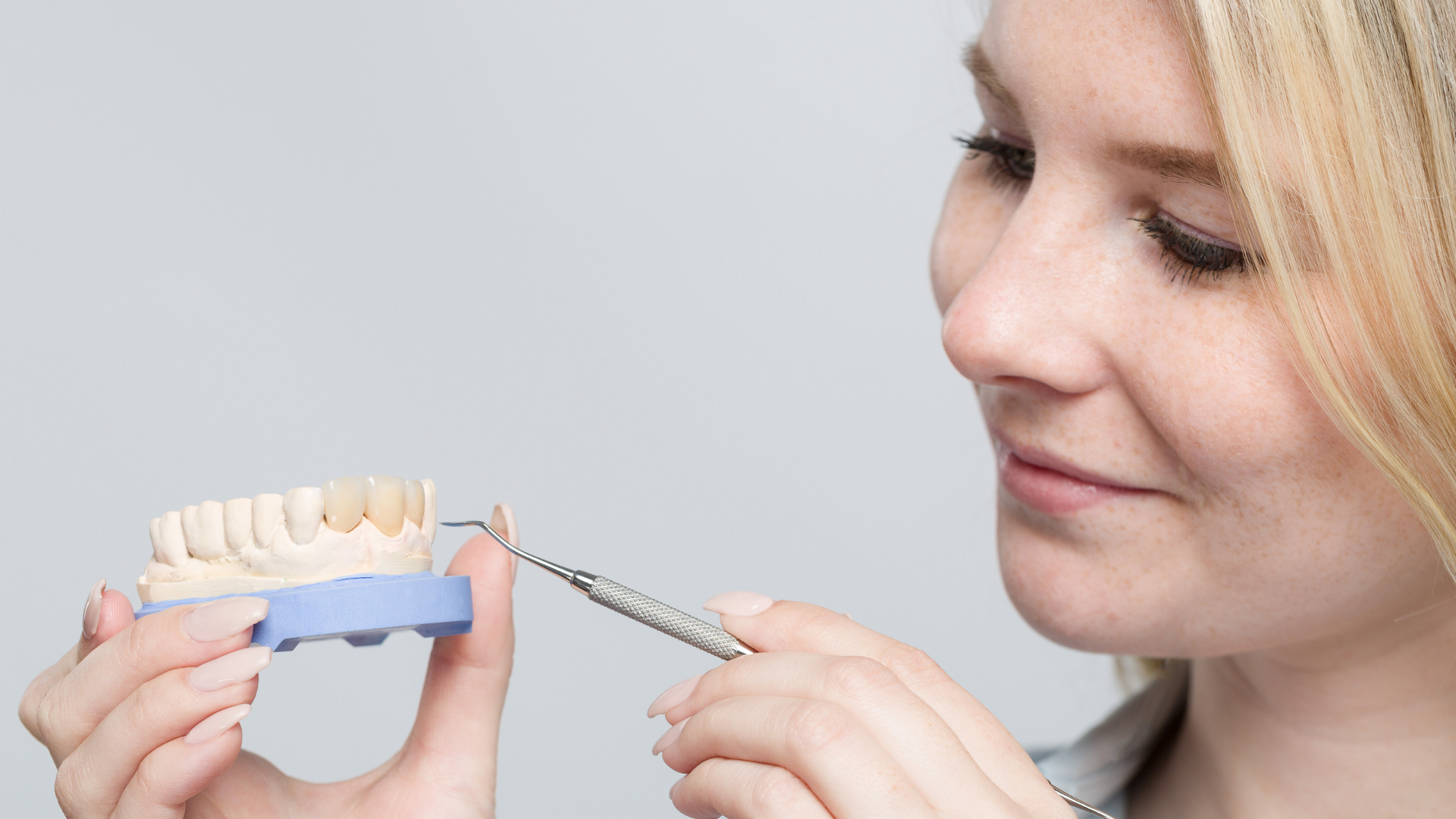 a woman is holding a model of teeth in her hands .