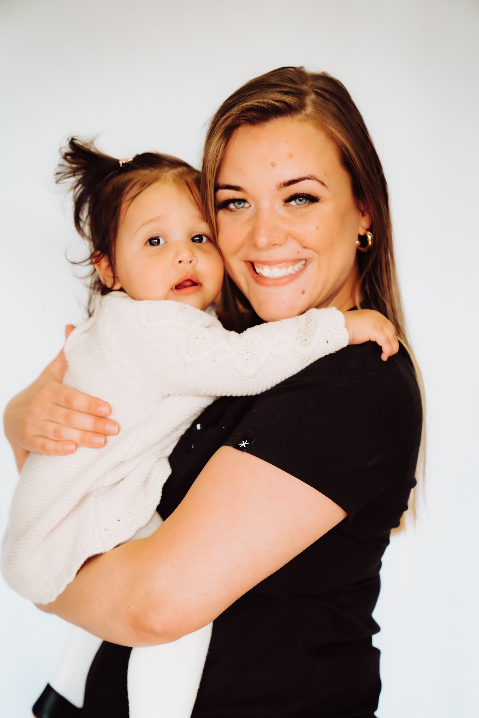 a woman is holding a baby in her arms and smiling .