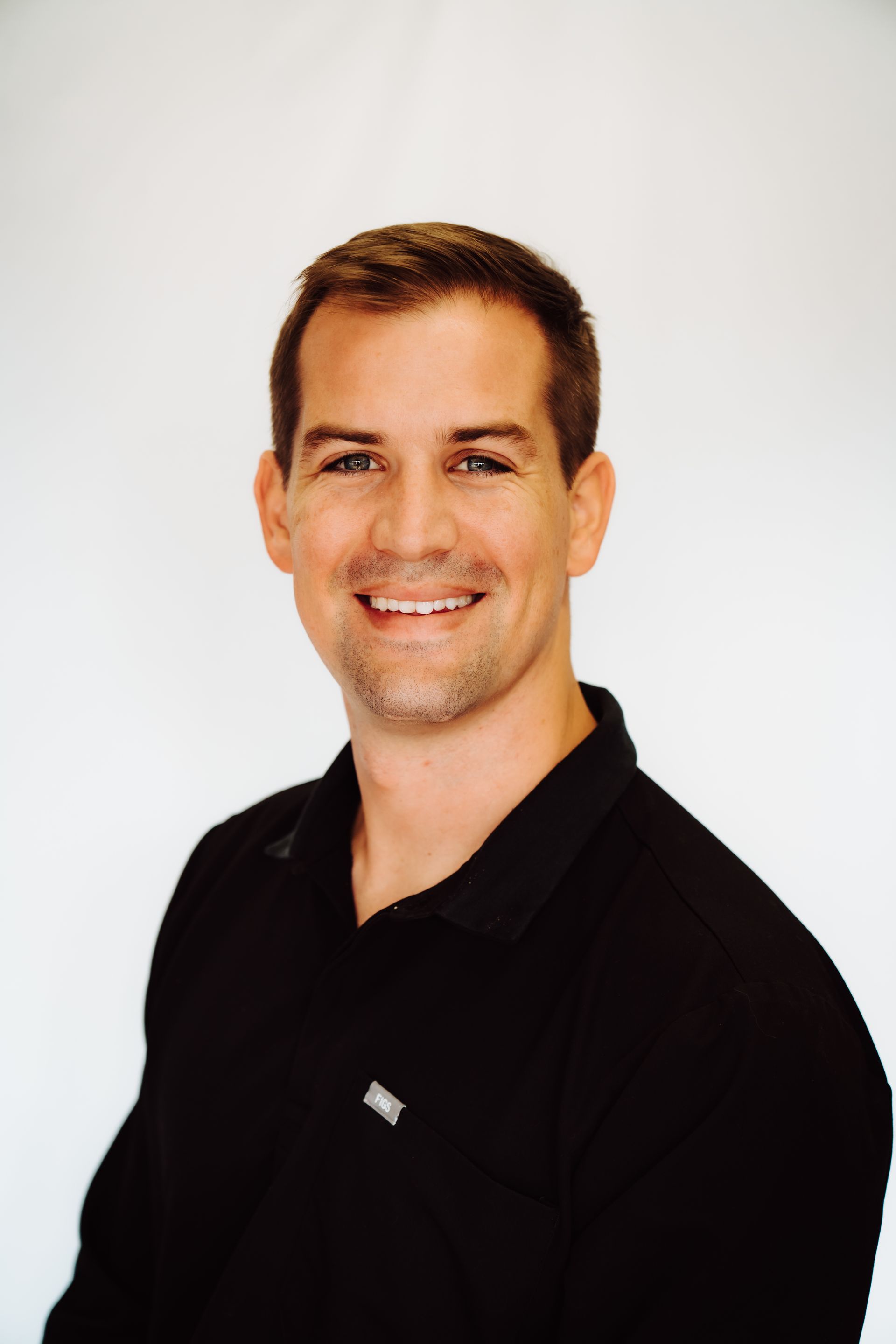 a man in a black shirt is smiling for the camera .