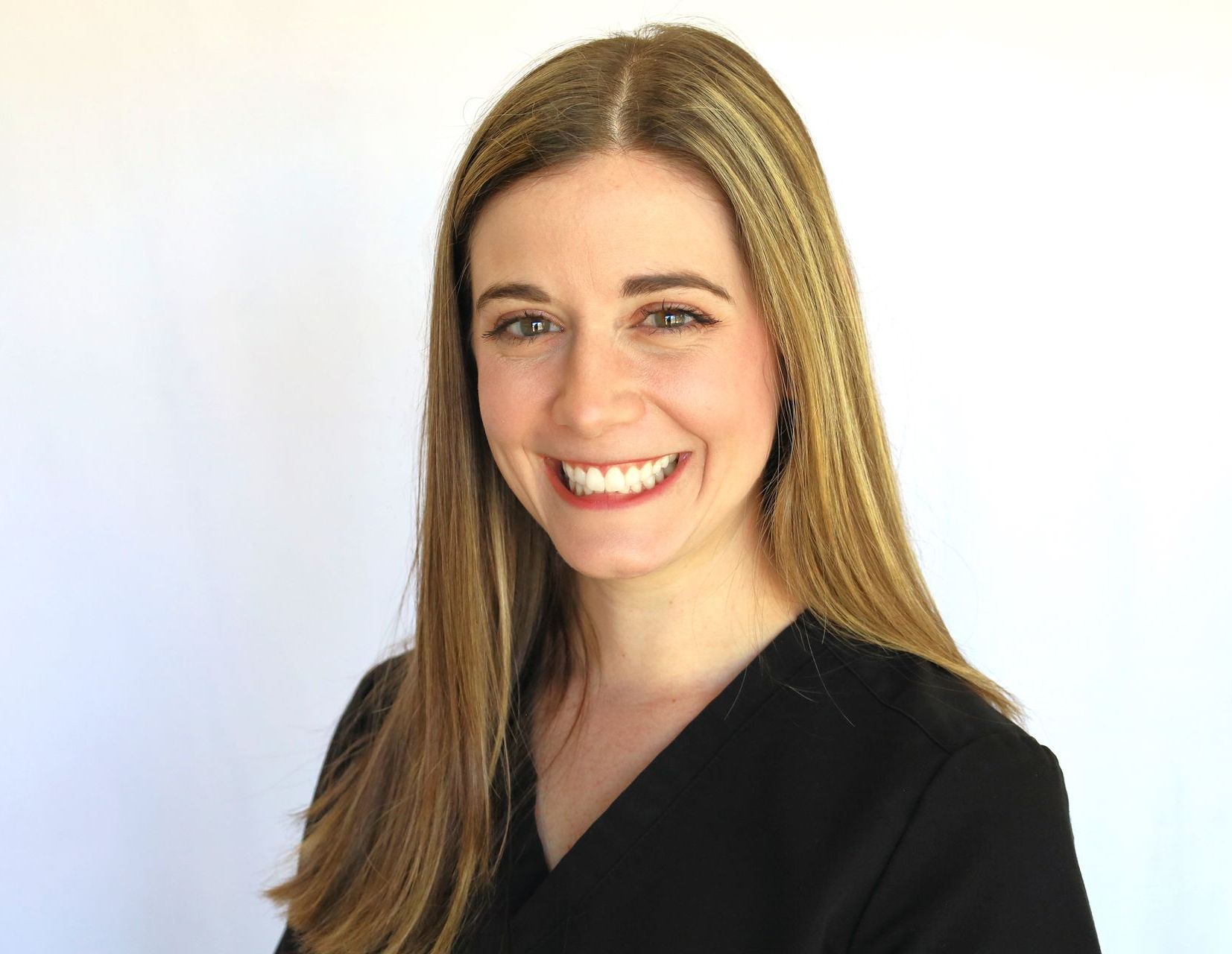 a woman in a black scrub top is smiling for the camera .
