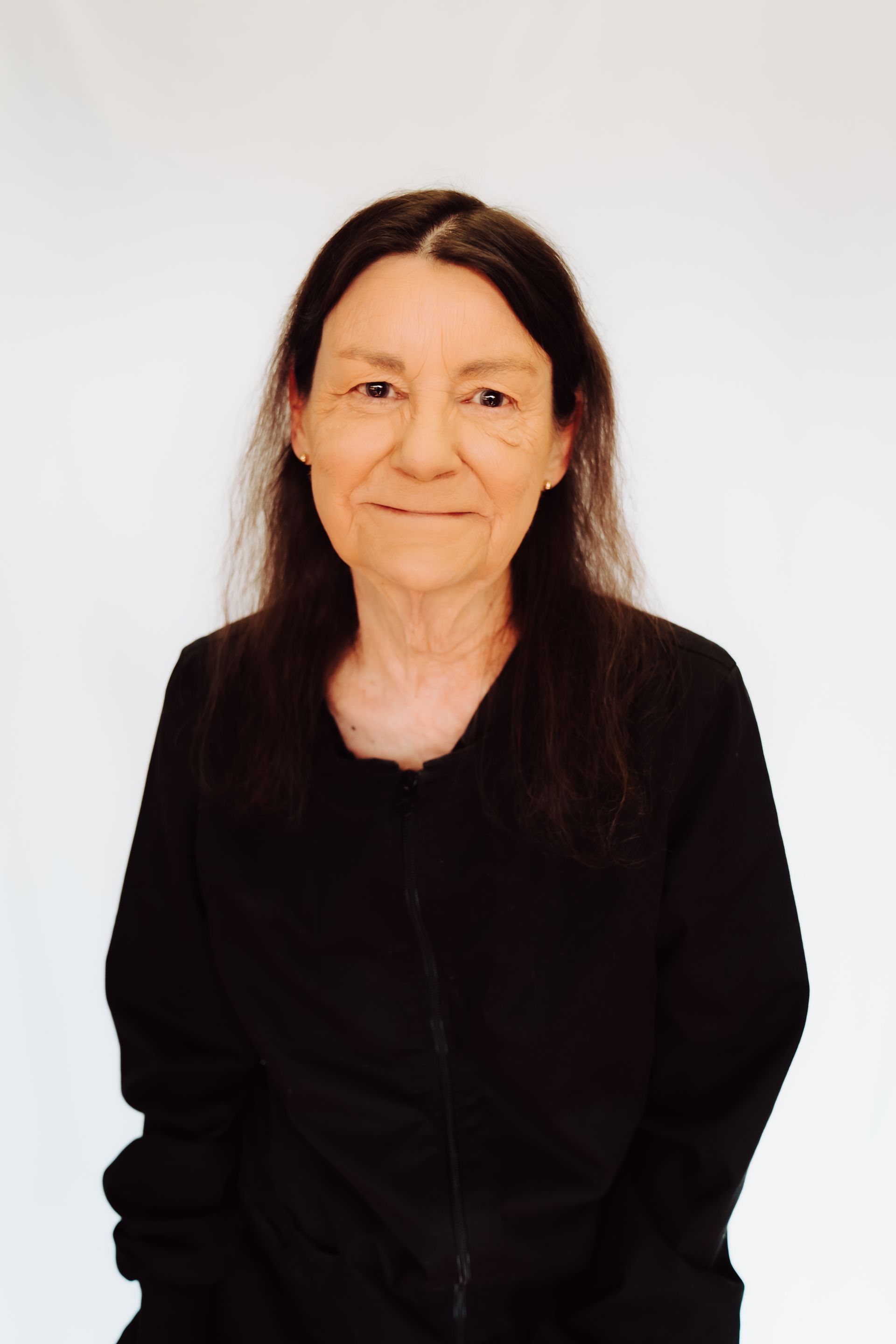 a woman with long hair is wearing a black jacket and smiling for the camera .