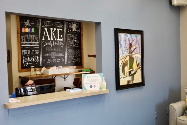 there is a chalkboard on the wall above the counter in the waiting room .