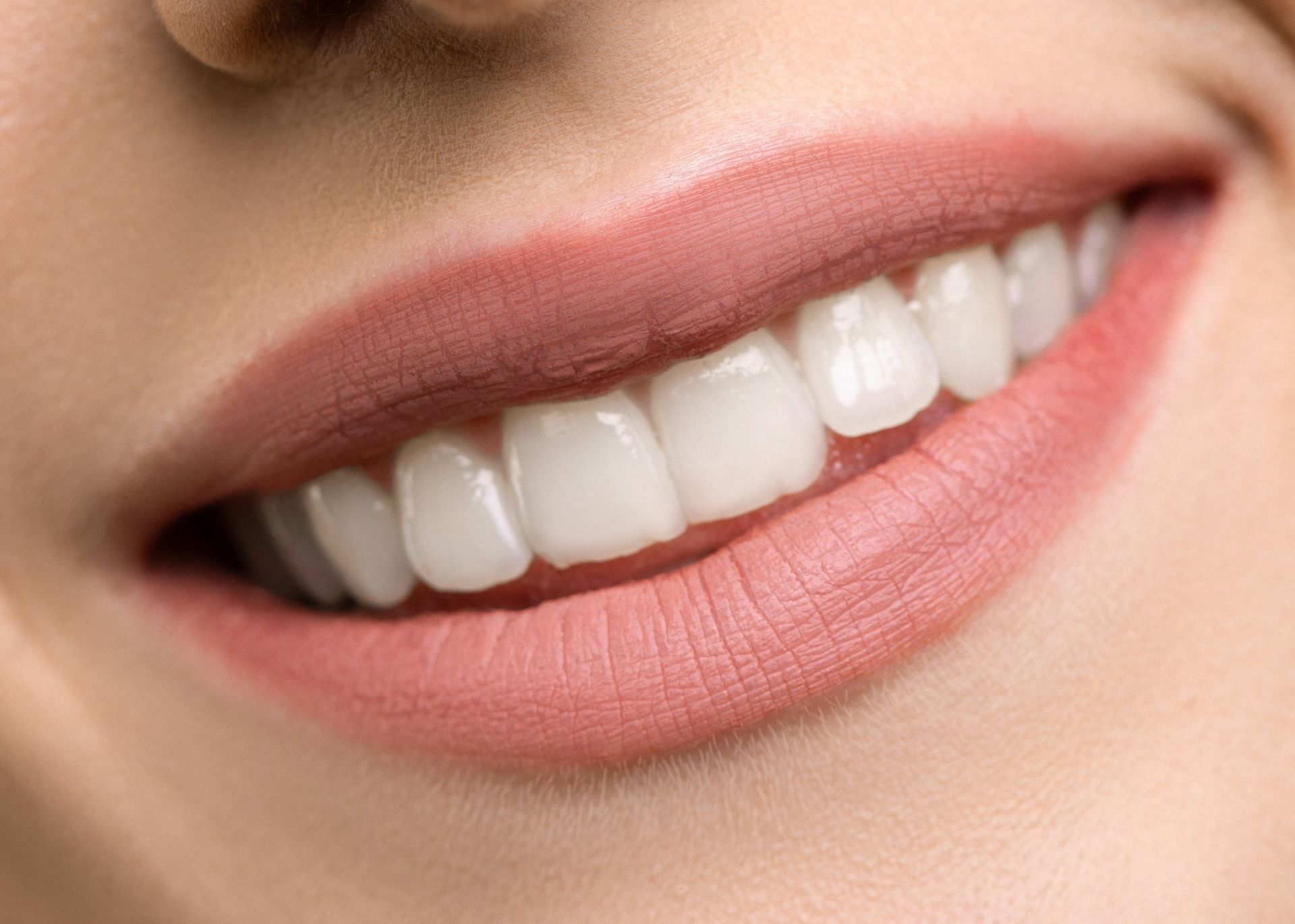 a close up of a woman 's smile with white teeth and pink lips .