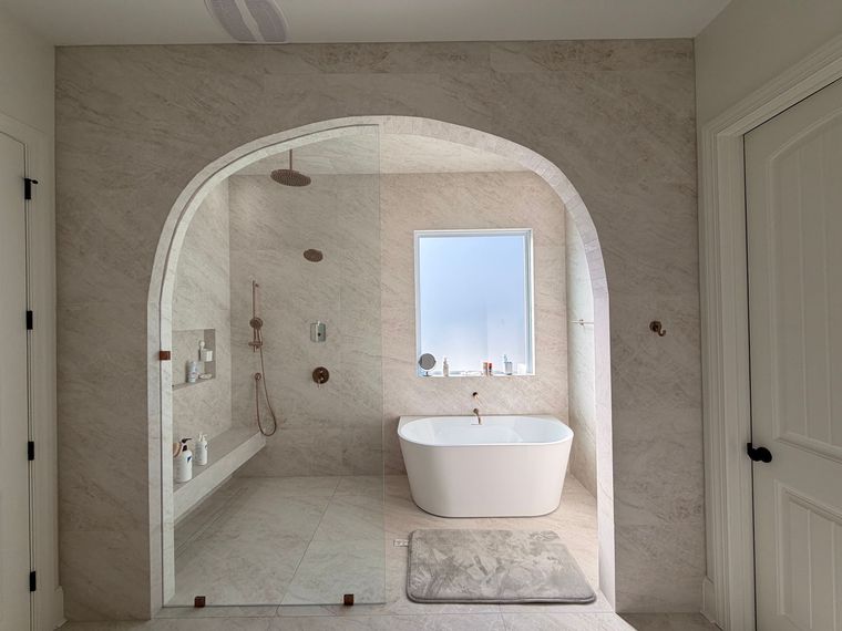A kitchen sink area with white subway tiles in a herringbone pattern, a storage tray with bottles, and a faucet.