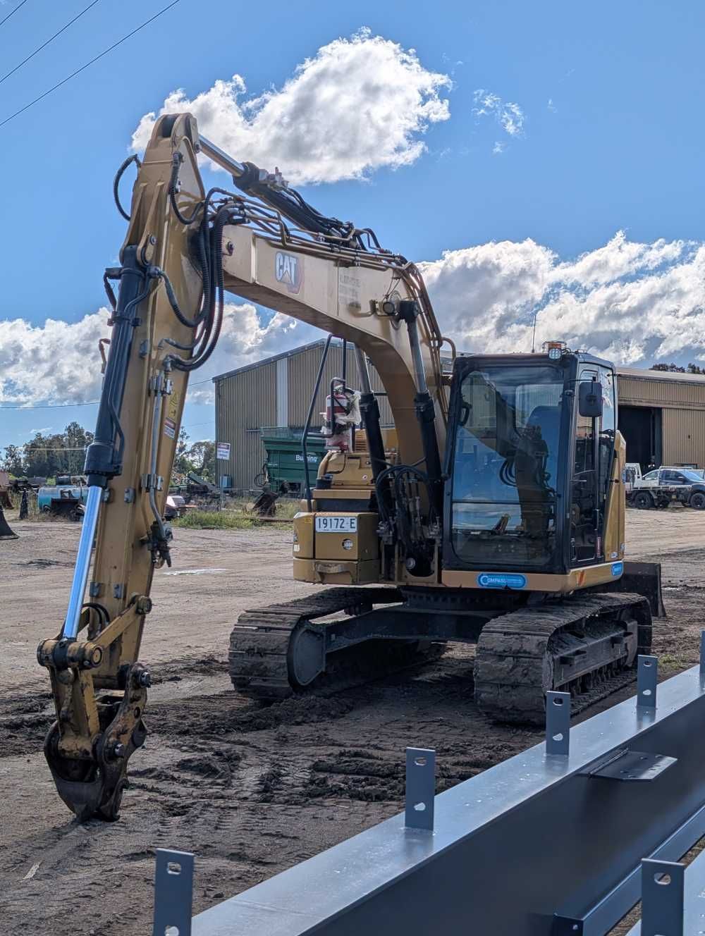 Yellow excavator parked at a construction site under a bright blue sky — Compass Equipment Hire in Mullumbimby, NSW
