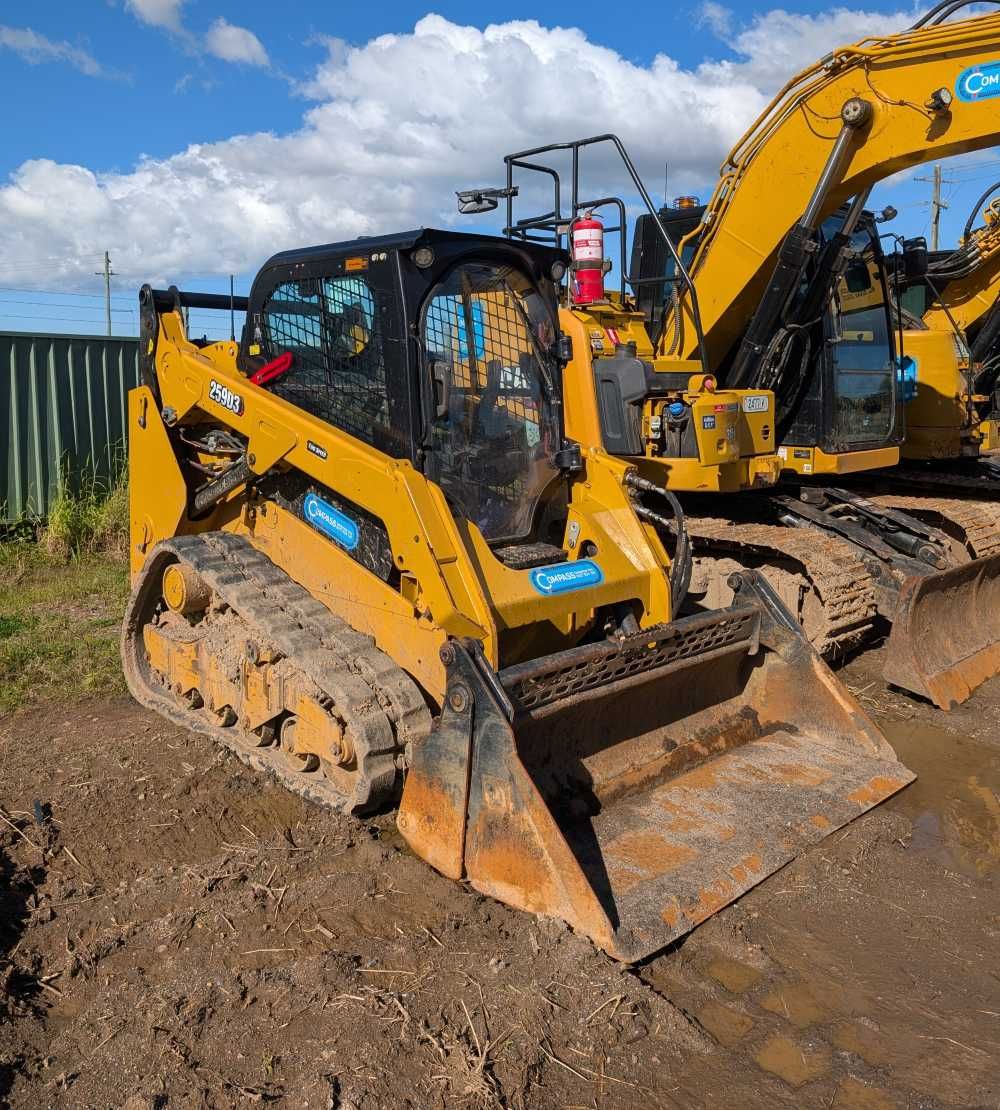 Yellow excavator on muddy ground at a construction site under a blue sky — Compass Equipment Hire in Brunswick Heads, NSW