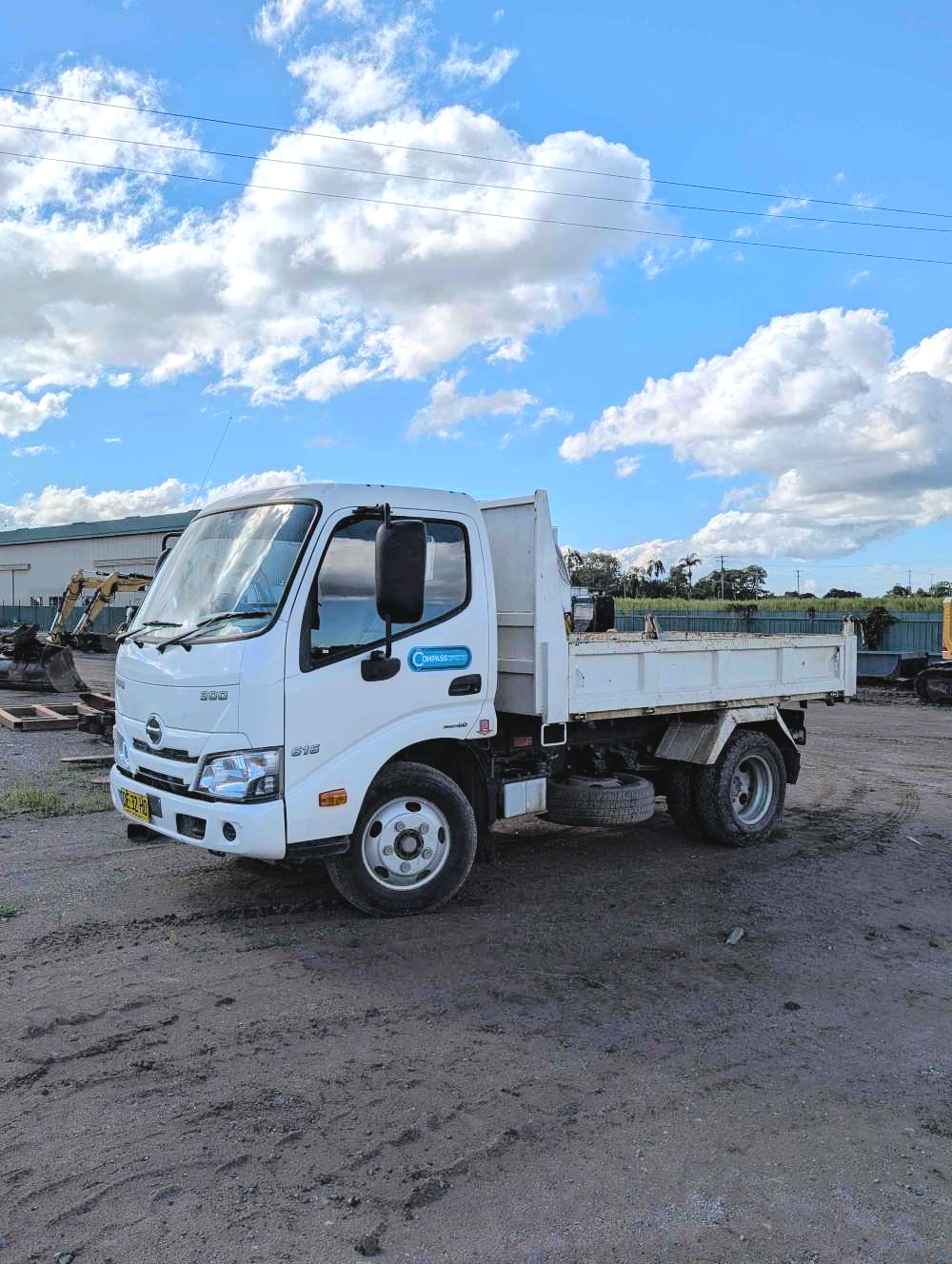 White truck parked on a dirt lot under a blue sky with clouds — Compass Equipment Hire in the Northern Rivers, NSW