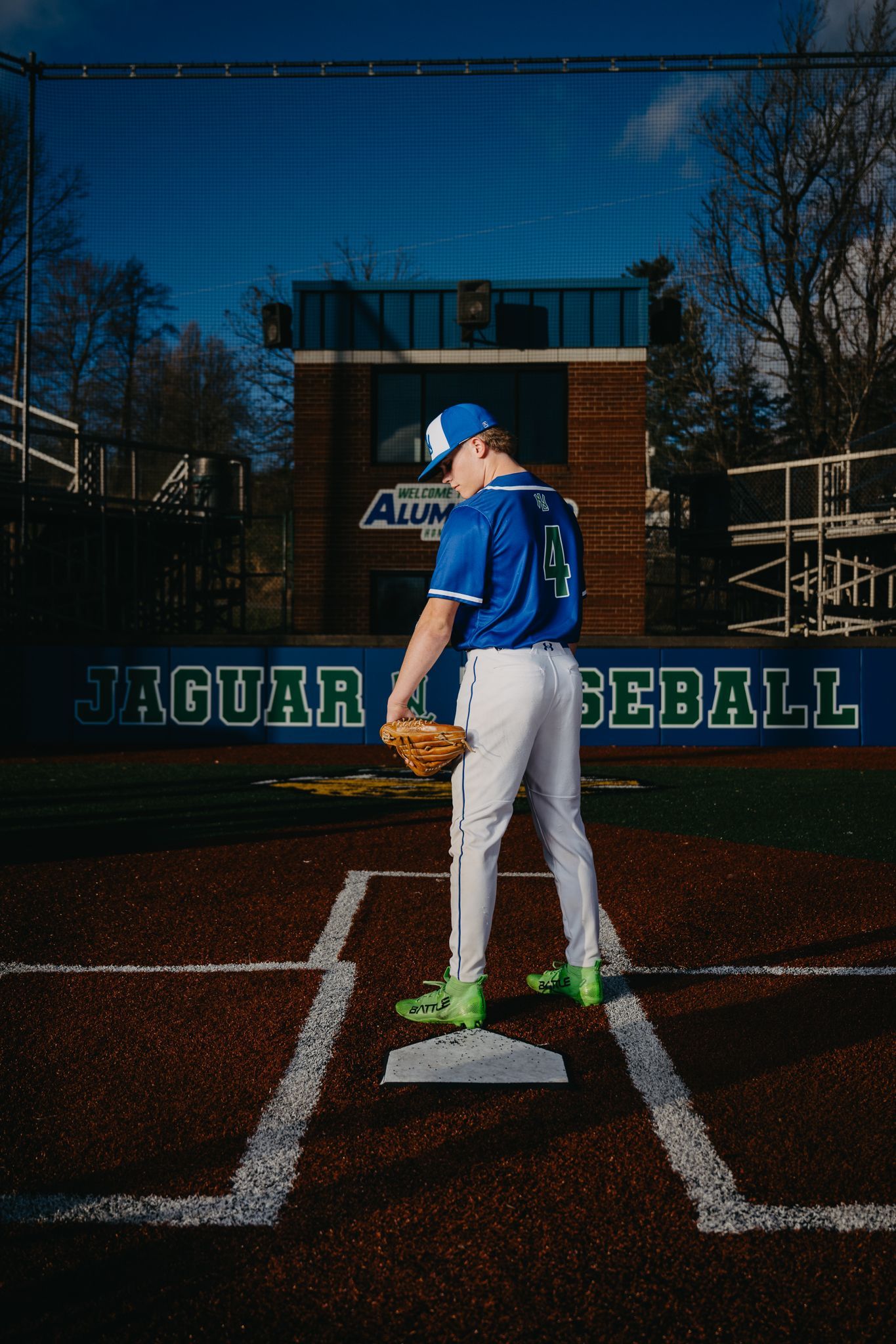 A baseball player in a blue uniform stands on a pitcher's mound in a stadium with