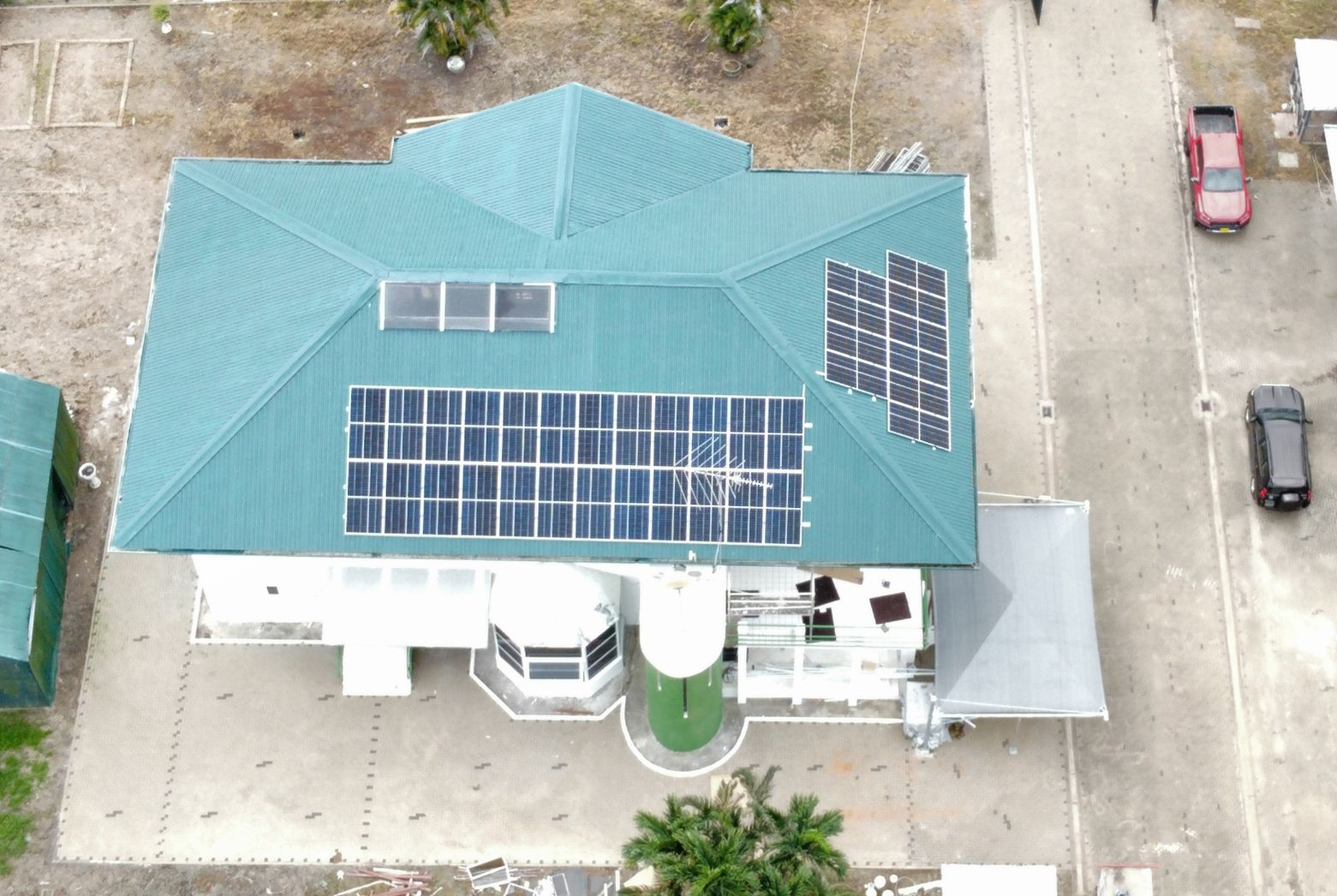 Zonnepanelen die een dak bedekken in fel daglicht, met zicht op de omliggende huizen.