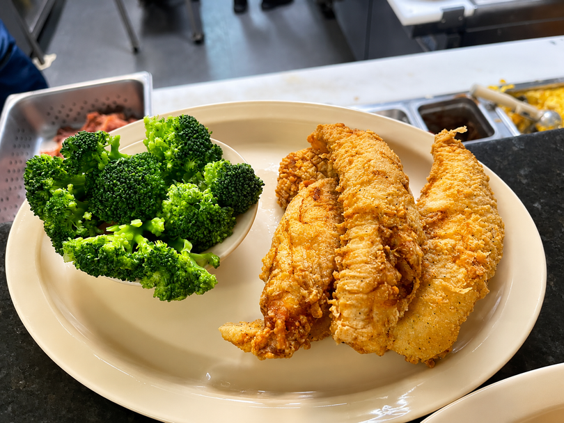Plate with fried chicken strips and broccoli on a cafeteria tray