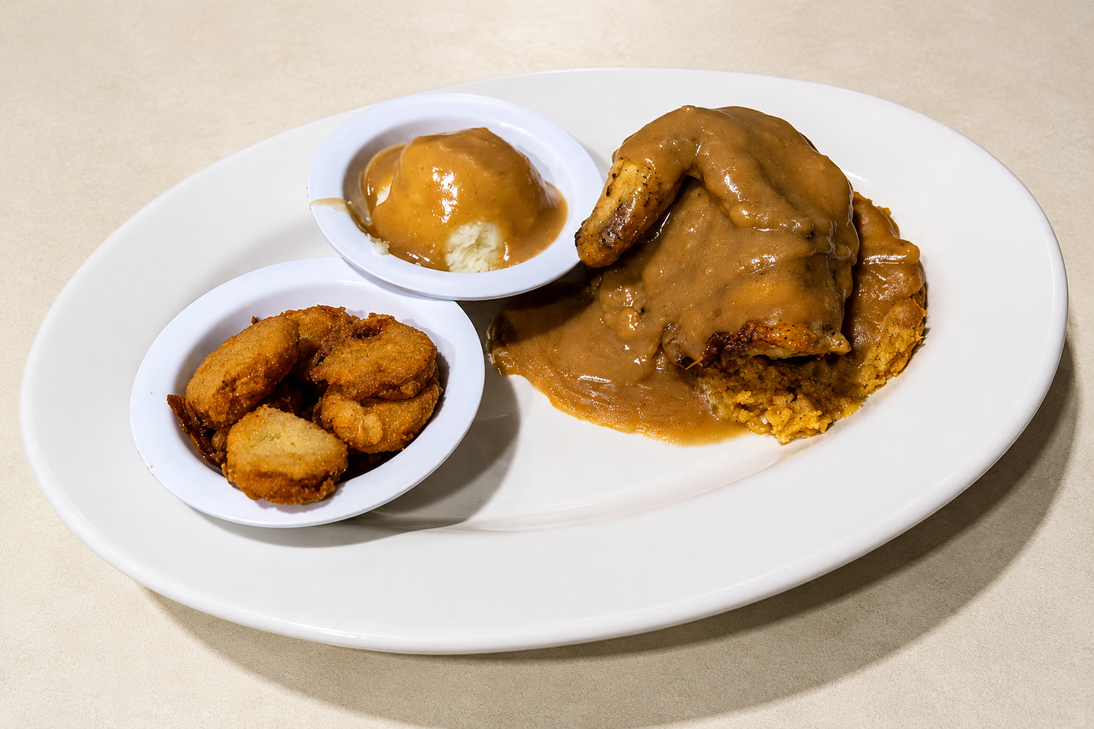 White plate with grilled chicken, sauce, and two small side dishes on a beige tabletop