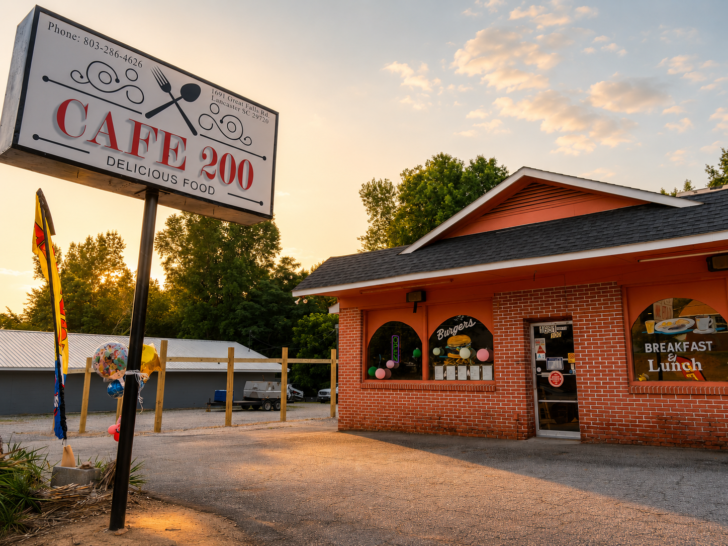 Cafe 200 brick storefront with sign at sunset, featuring a red roof and gravel parking area