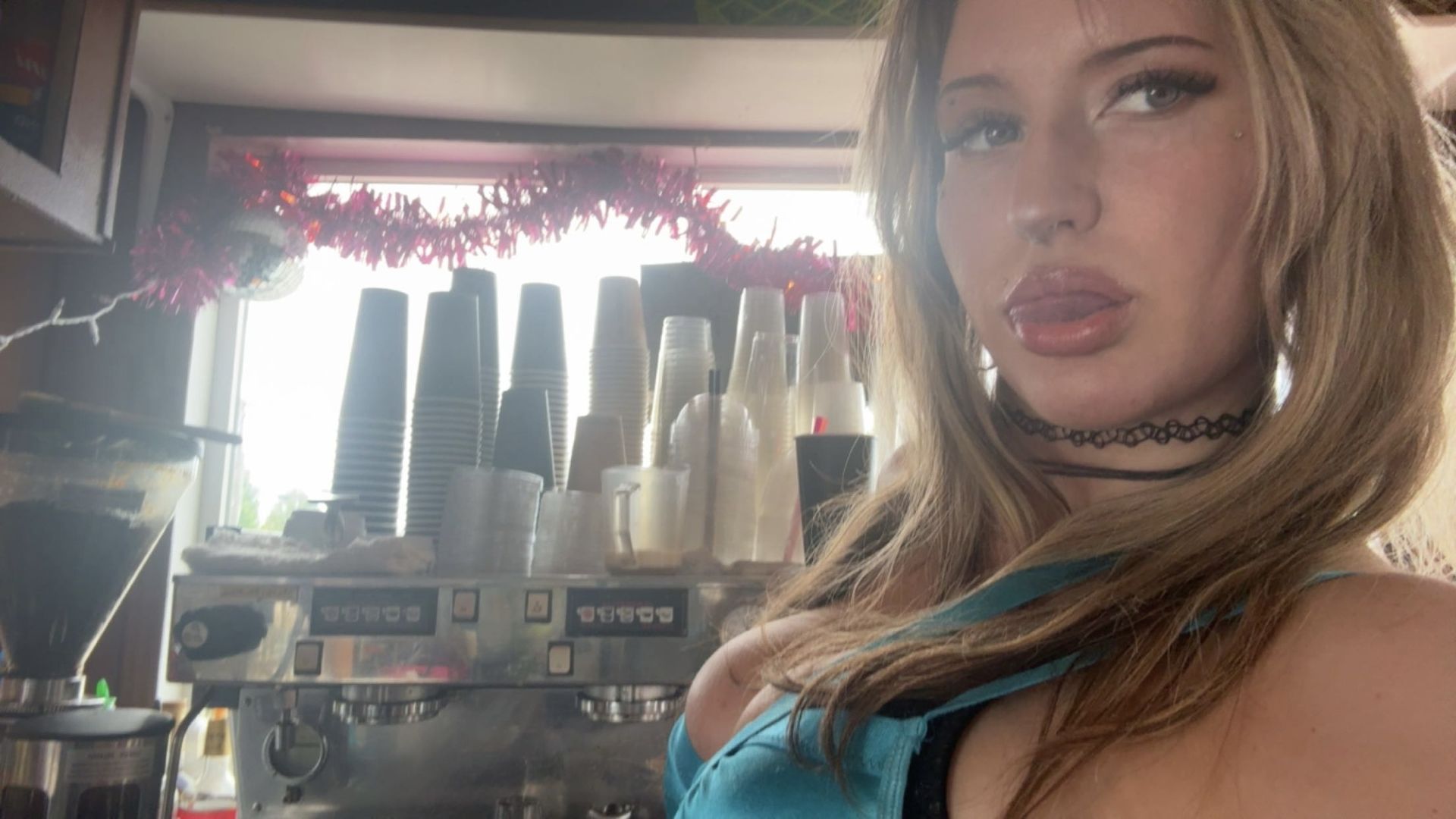 Blonde woman in lingerie, puckering lips. Indoors, low light.