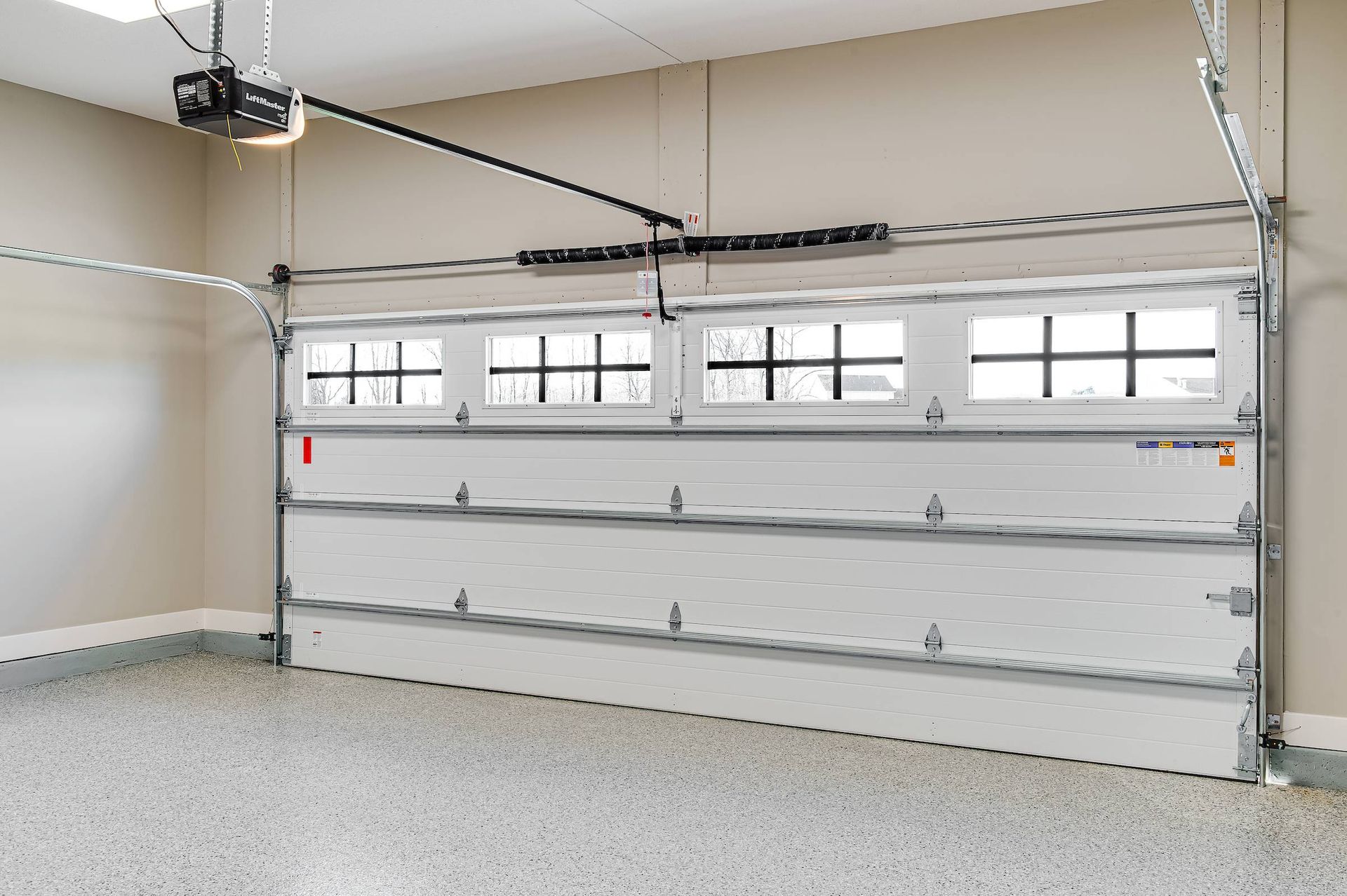 Empty two-car garage with a white sectional door and overhead opener.