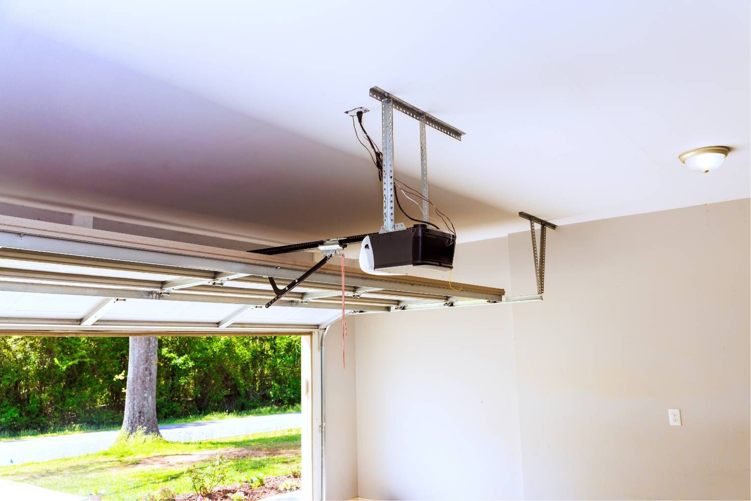 Damaged garage door opener hanging from the ceiling in an open garage