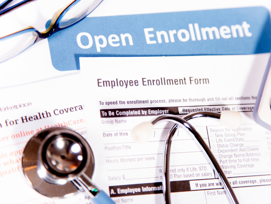 Open enrollment form with magnifying glass and eyeglasses on papers