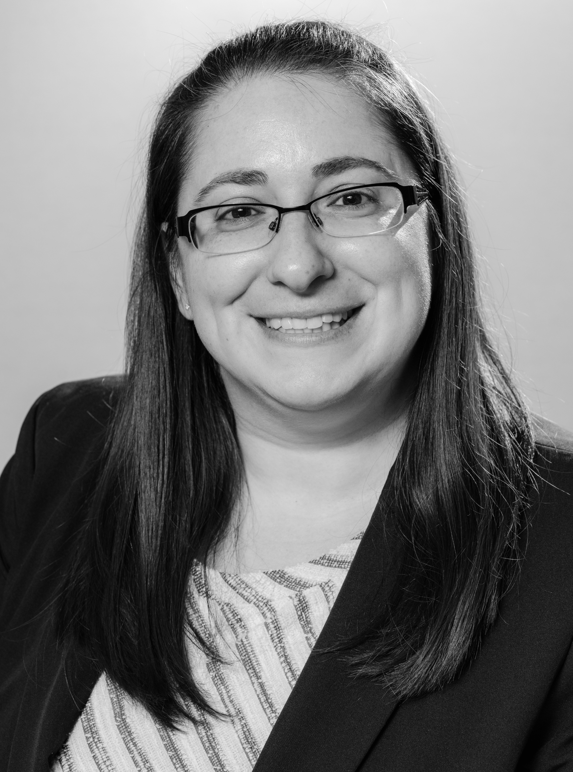 A woman in a red shirt and necklace is smiling for the camera.