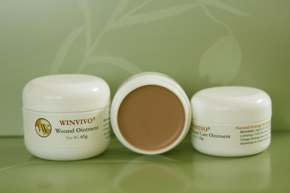 Three small white jars of beauty cream, one open, with a light brown colored cream inside.