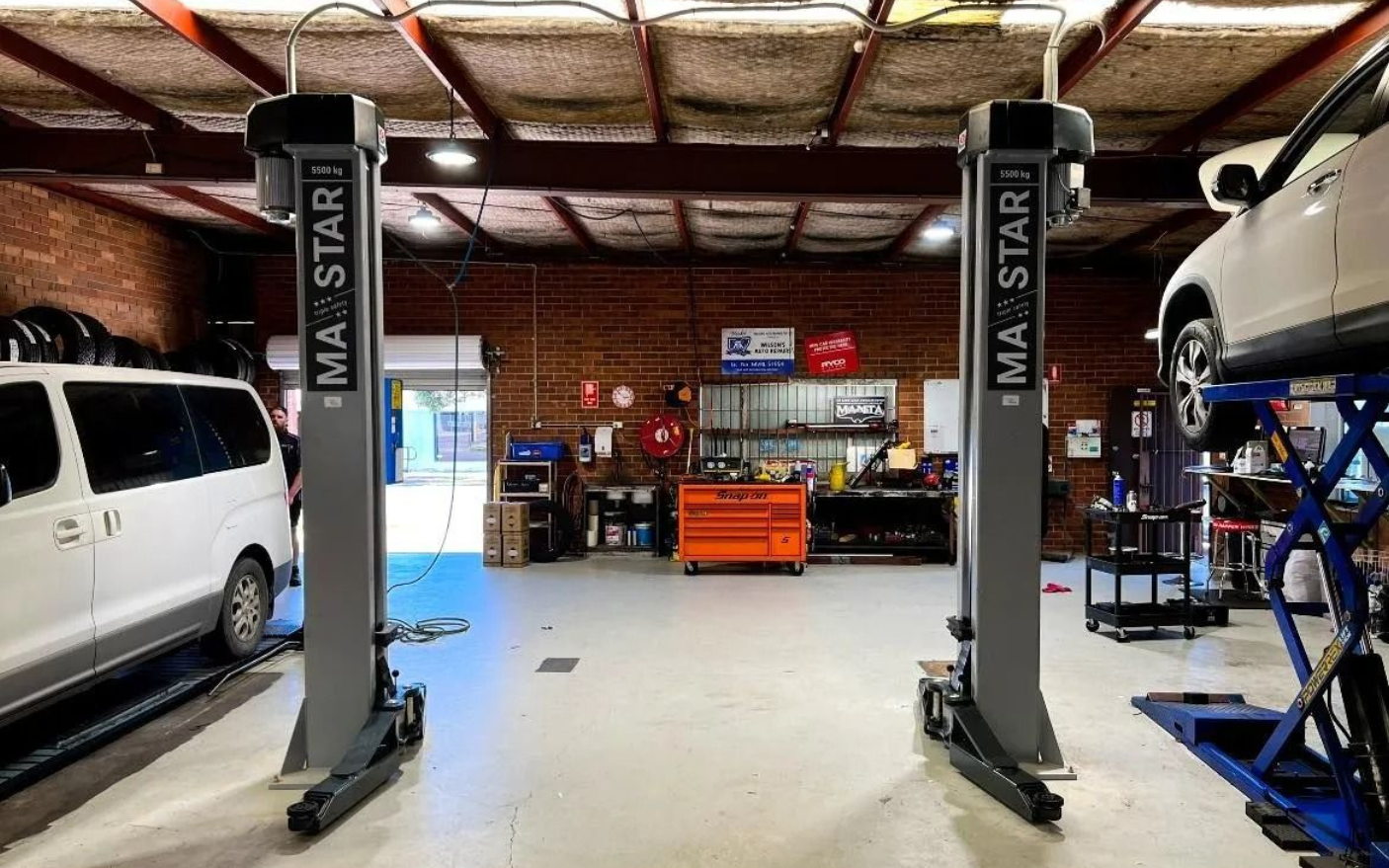 Auto repair shop interior with a car lift, vans, and a workbench in the back