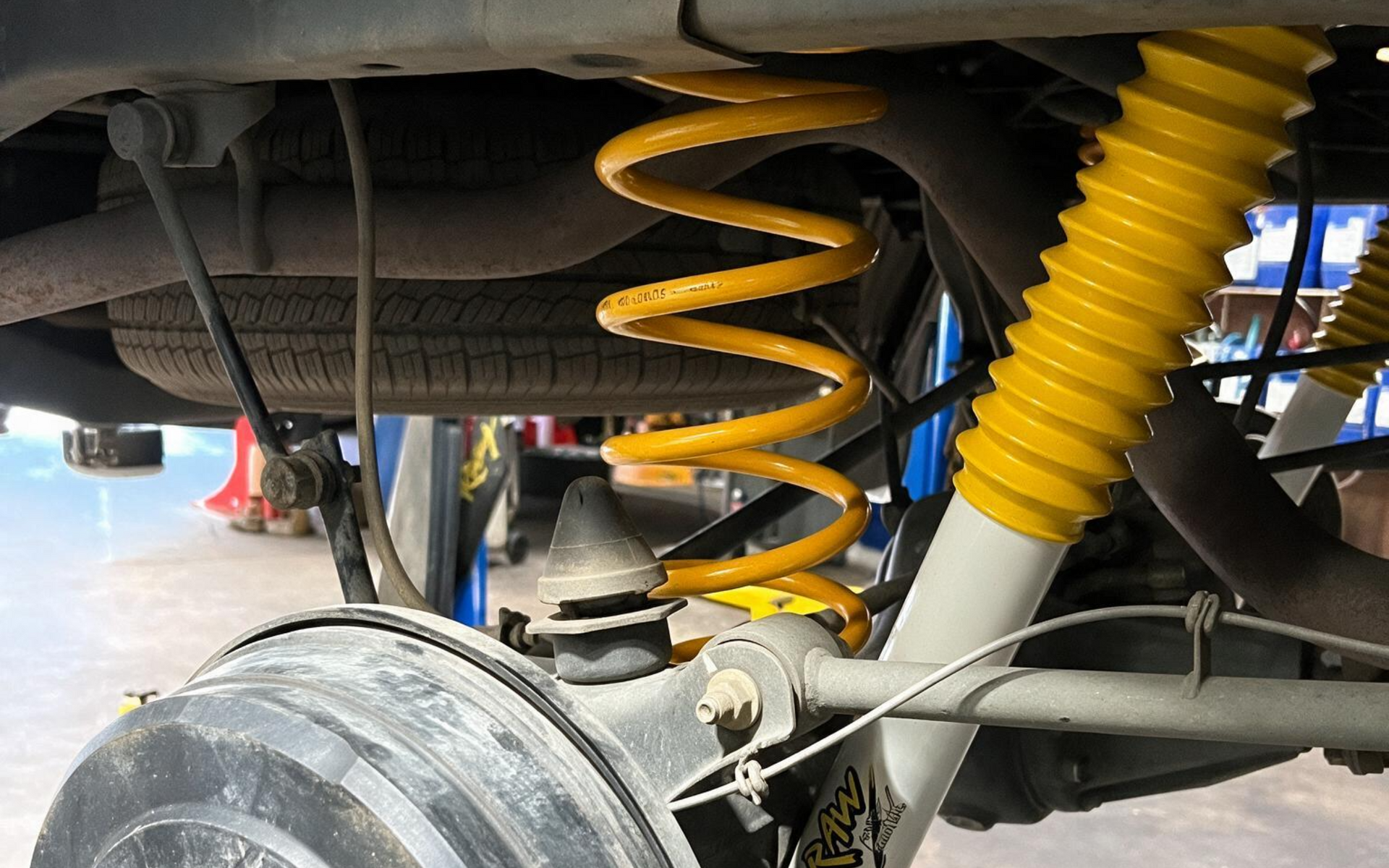 Close-up of car suspension with yellow coil springs and wheel assembly