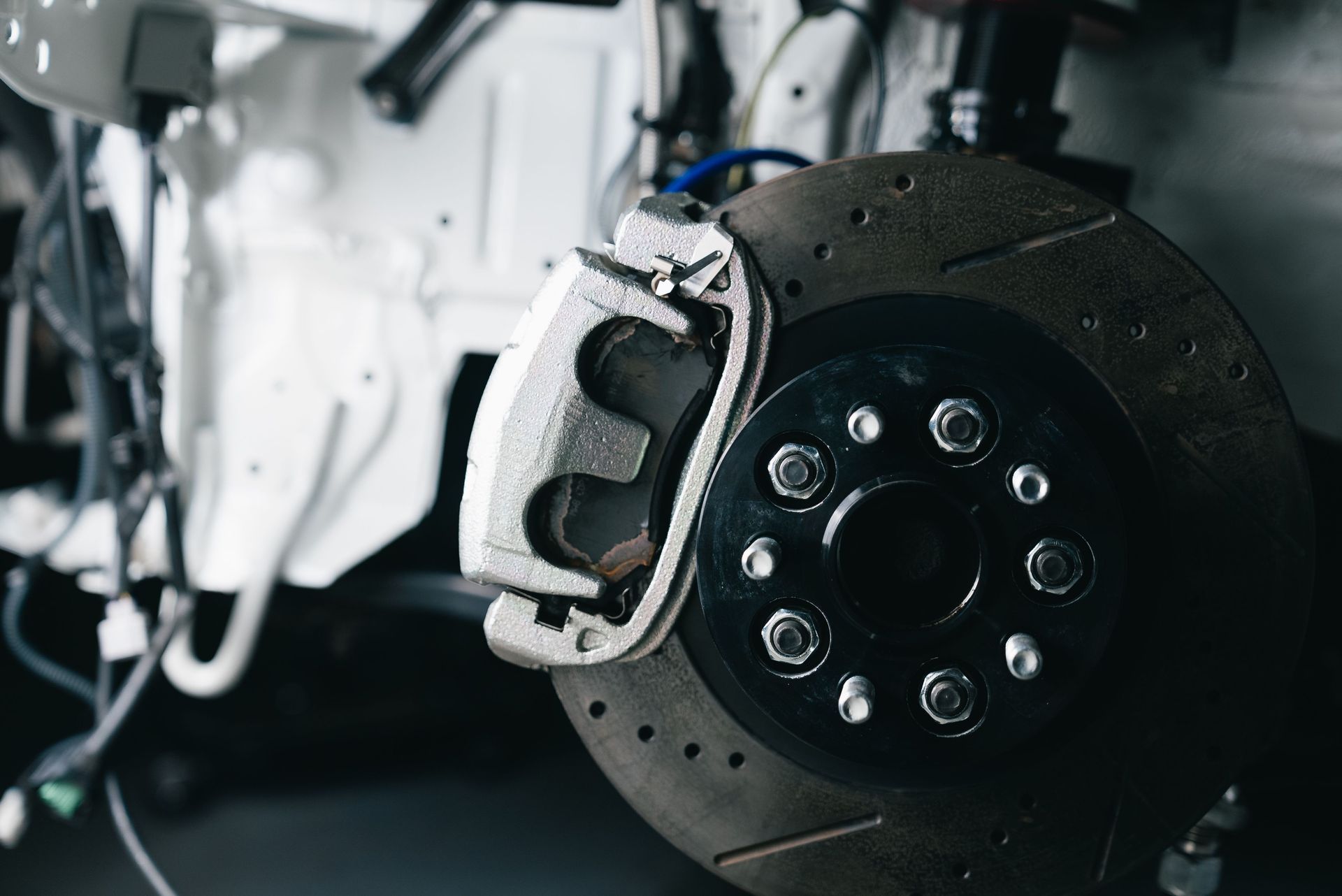 Close-up of a car’s exposed front brake rotor and caliper during repair