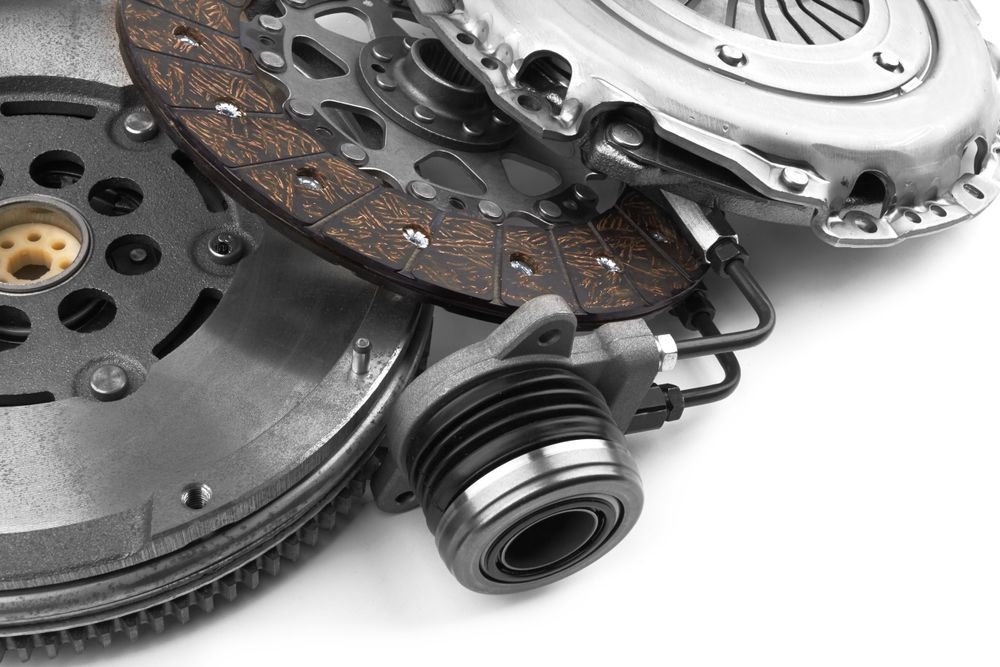 Close-up of a worn car clutch assembly with pressure plate, disc, and release bearing on a white background