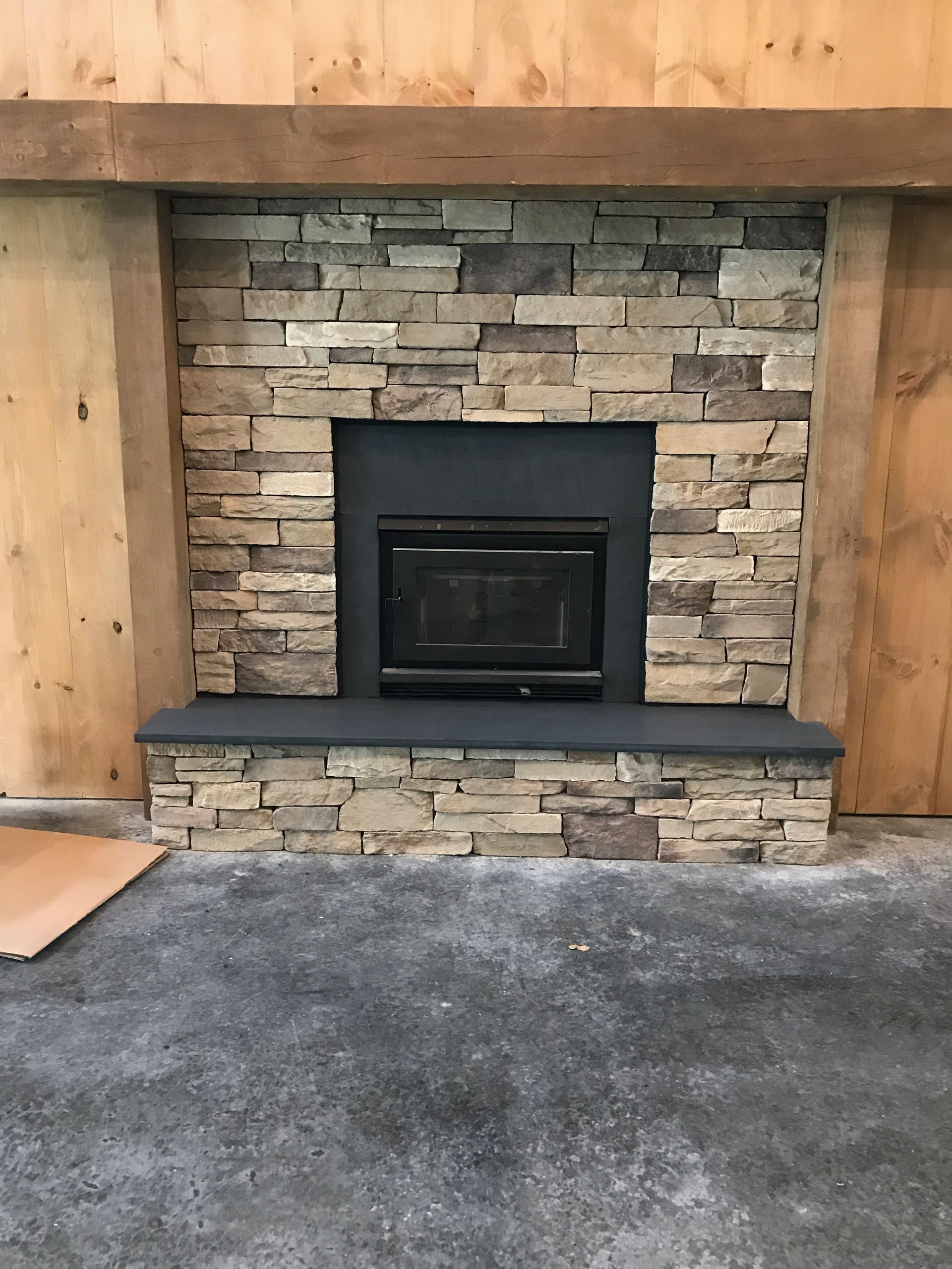 A stone fireplace with a black stove in it