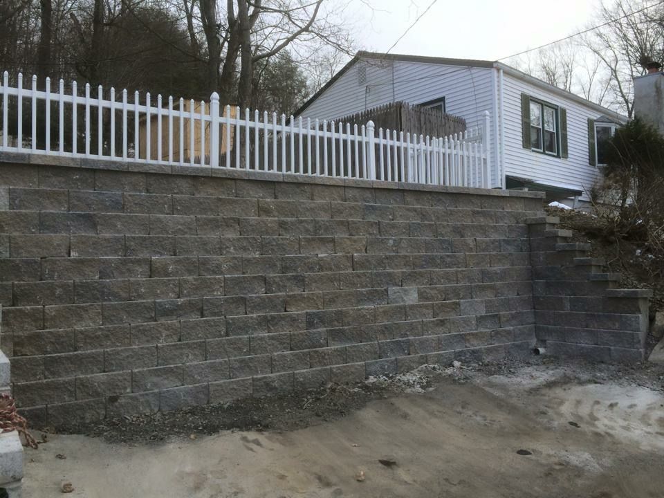 A brick wall with a white picket fence in front of a house.