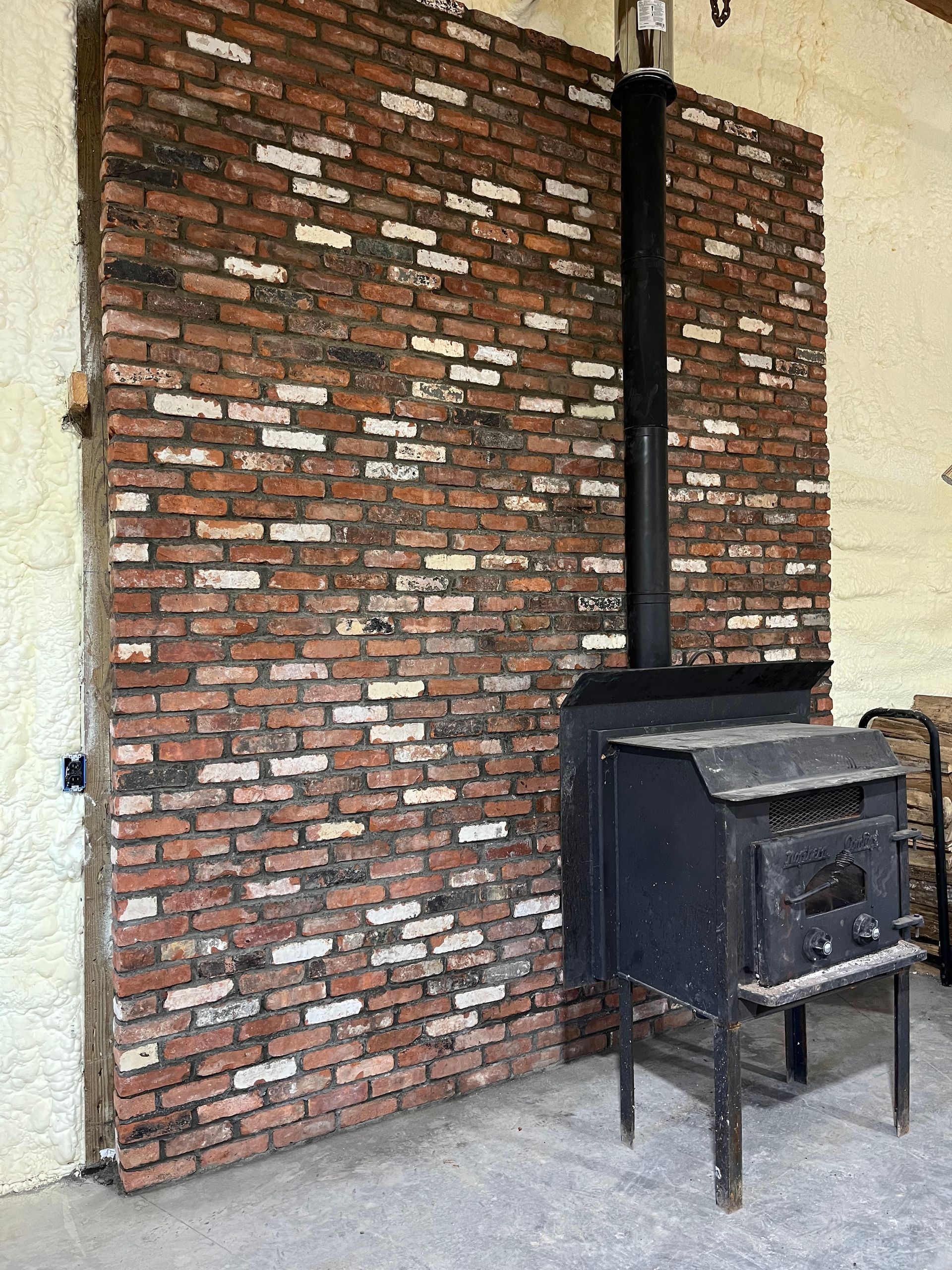 A wood stove is sitting in front of a large brick wall.