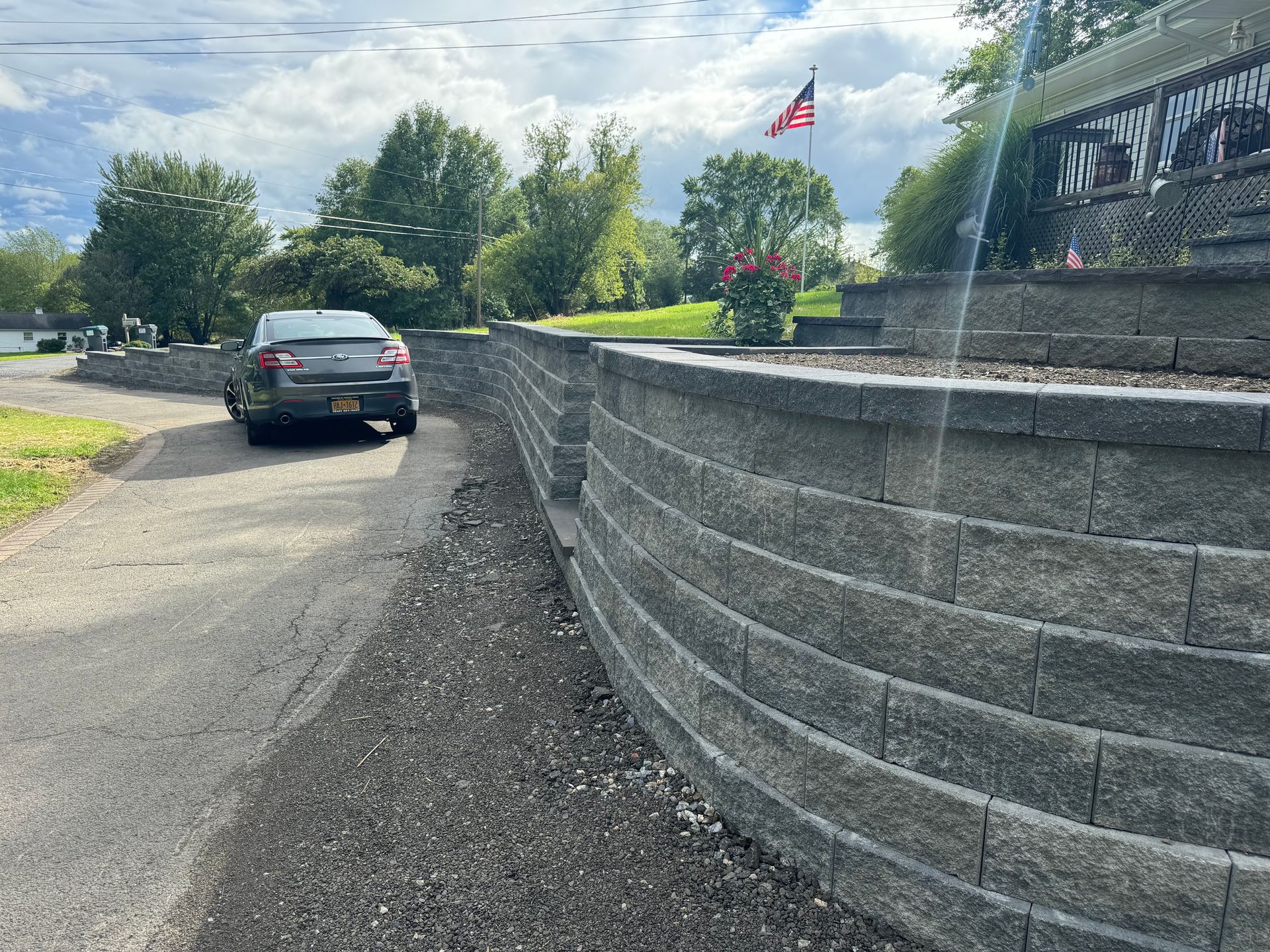 A car is parked on the side of a road next to a stone wall.