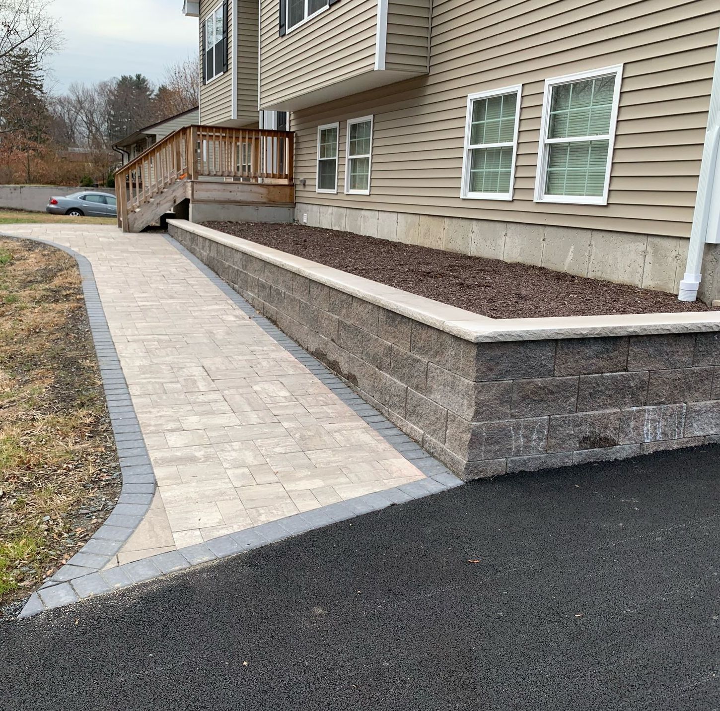 A brick walkway leading to a house with a deck