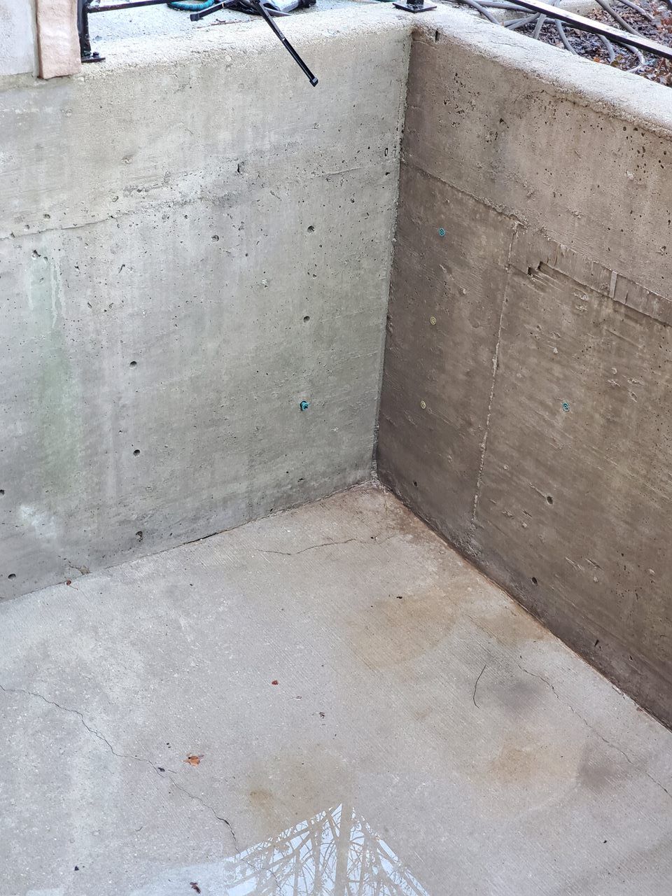 Concrete corner of a structure, floor and walls. Sunlight on the floor.