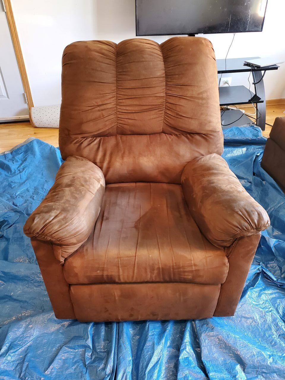 Brown recliner chair on a blue tarp; room setting.