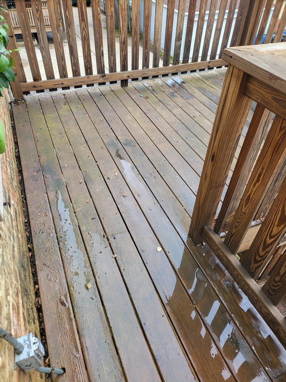Wooden deck with wet surface and railing; exterior shot.