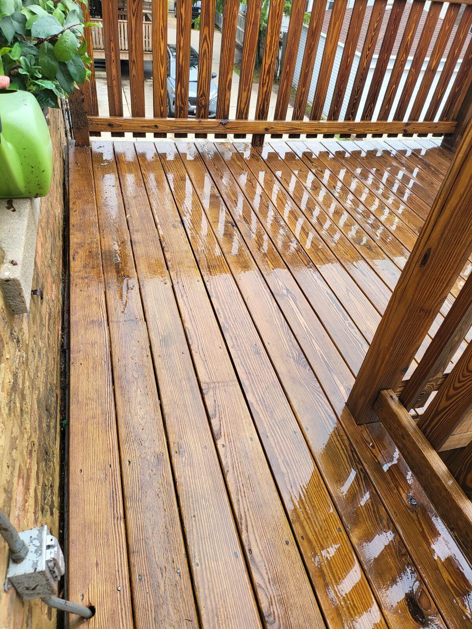 Wooden deck with wet, glossy stain and a wooden railing.