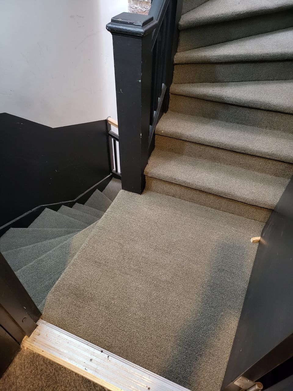 Staircase with carpeted steps and dark wood banisters, leading downwards.