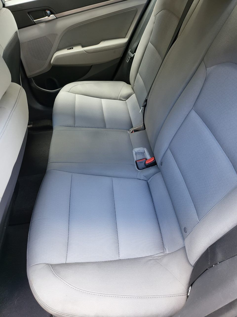 Back seat of a gray car. Seatbelts are visible. Interior is gray and black.