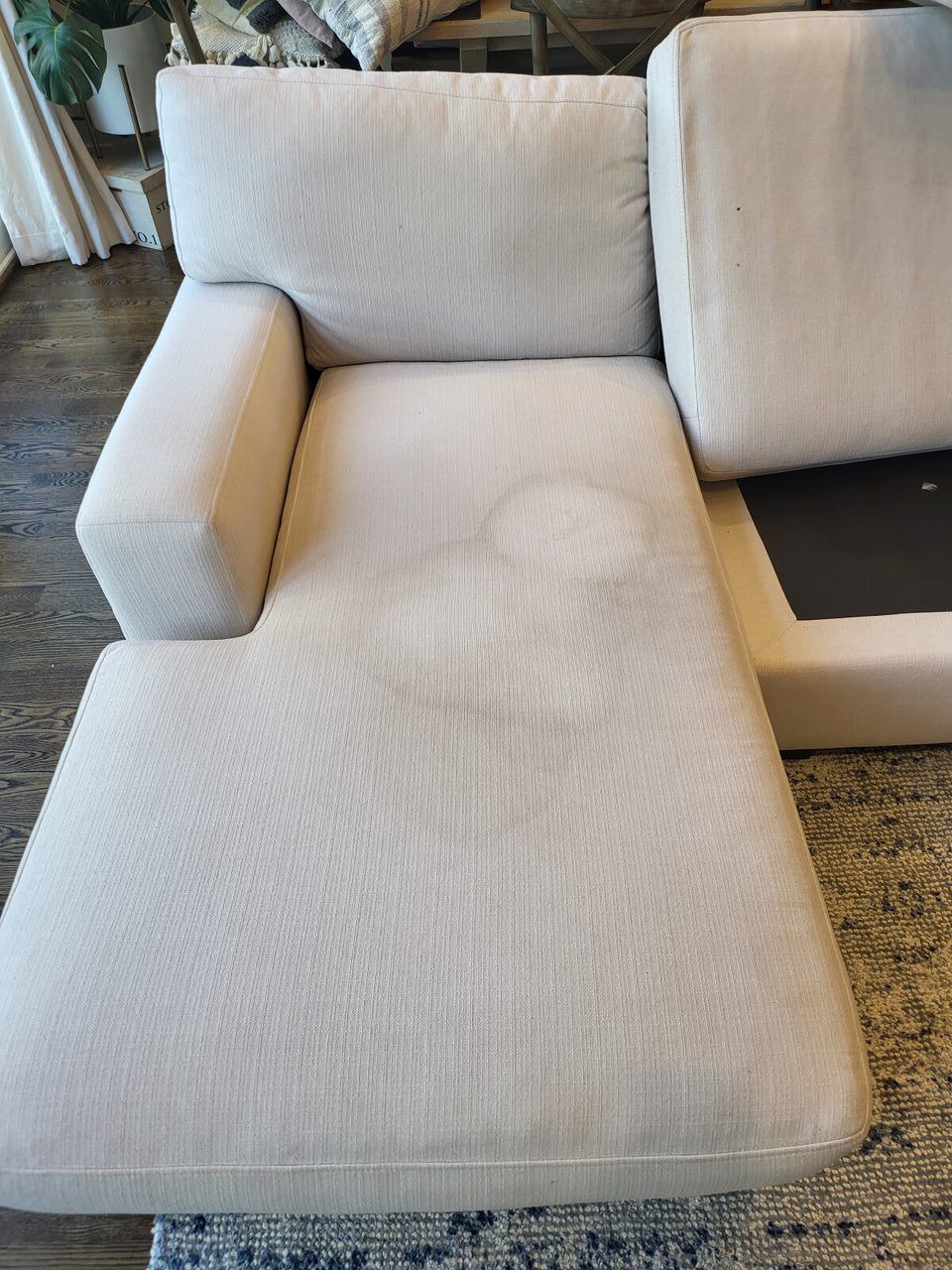 Beige sectional sofa with stains on the chaise lounge.