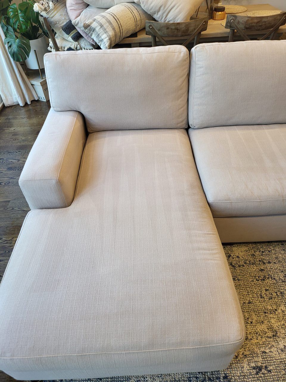 Beige sectional sofa in a room with a light-colored rug and decorative items.