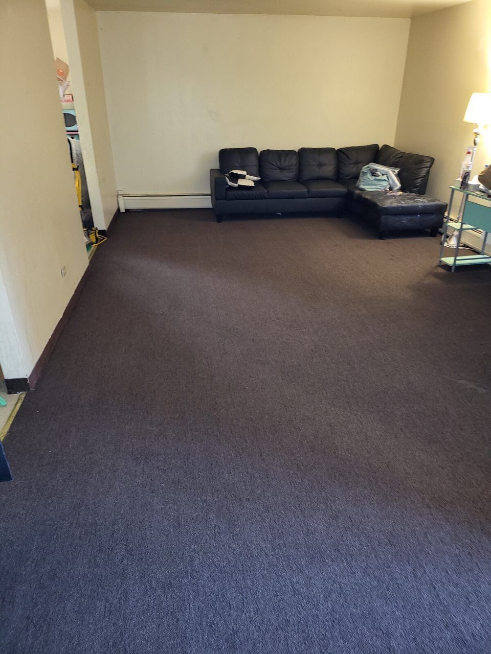 Living room with dark brown carpet and black sectional sofa.