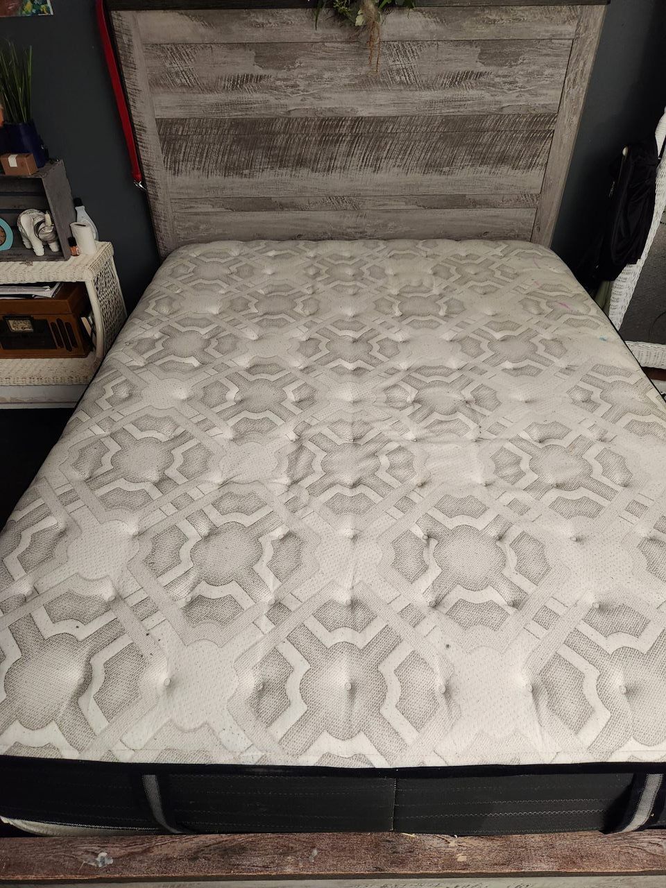 Queen-sized bed with a weathered wooden headboard and a white patterned mattress.